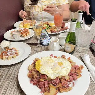 Corn beef hash with 2 eggs  over easy, one waffle  with Bavarian cream and a mango  mimosa.