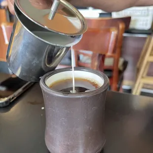 a person pouring a cup of coffee