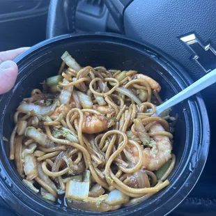 a hand holding a bowl of noodles