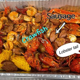  a container full of lobster, corn and sausage
