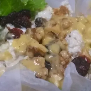 This close up is a chicken salad lettuce wrap with cranberries, walnuts, chicken, mayo and maybe dijon mustard.