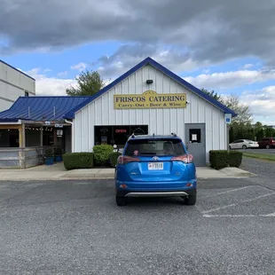 a blue car parked in front of a restaurant