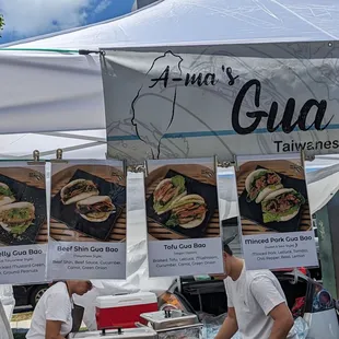 shows two men preparing food under a tent