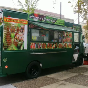 a green food truck parked on the side of the street