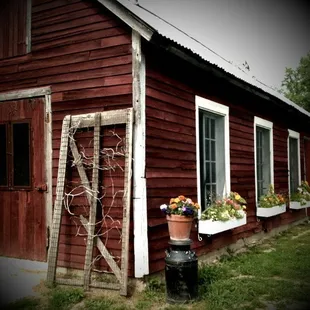 a red barn with a ladder and flower pots