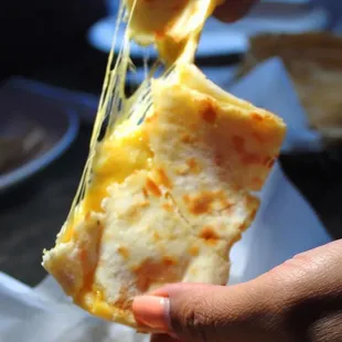 a hand holding a piece of cheese pizza