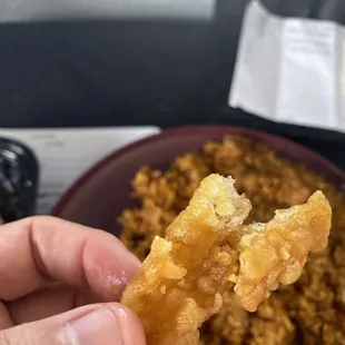 a hand holding a piece of fried food