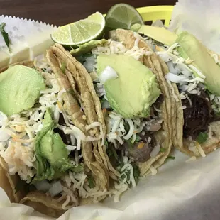 Tacos de carnitas (pork) and tacos de cabeza (steak), both with cheese and avocado.