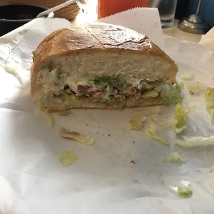 Half of a vegetarian torta. Delicious soft bread, lettuce, tomatoes, avocado, sour cream, and beans.