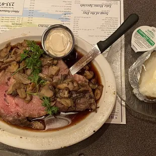 a plate of meat with mushrooms and mashed potatoes