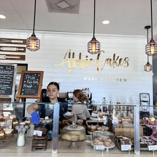 a woman behind the counter of a bakery