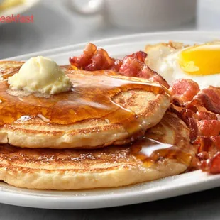 a plate of pancakes with bacon and eggs