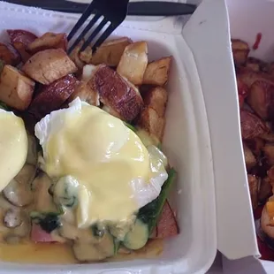 a plate of eggs benedict and potatoes