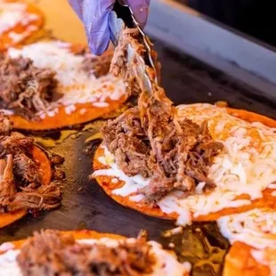 a person putting toppings on a pizza