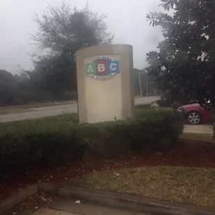 a red car parked in front of a sign