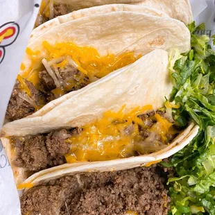 three tacos with cheese and lettuce