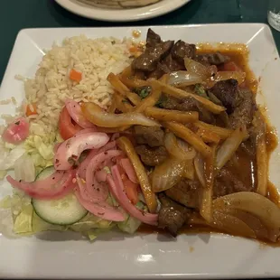 Lomo Saltado (also available in checked) is tender steak pieces in a tomato gravy over Frieda - side of salad and rice.