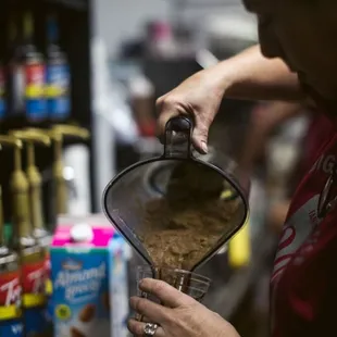 a woman pouring coffee into a blender