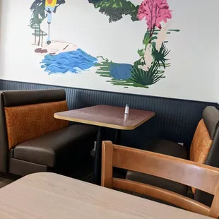 a table and chairs with a mural on the wall