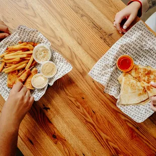 two people eating pizza and fries