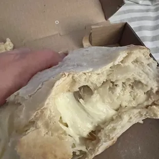 a hand holding a half eaten pizza