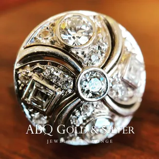 Spin me like a top! Propose with this antique platinum button ring. It shimmers and shines with 1.75cts of rounds and step cut diamonds.
