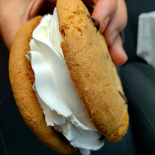 a person holding a cookie with whipped cream