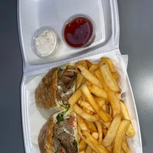 a sandwich and fries in a styrofoam container