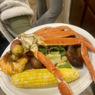 a plate of crab legs, potatoes and corn