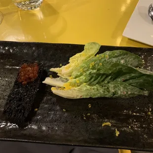 a black plate with lettuce and bacon