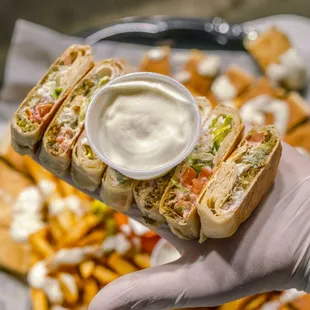 a hand holding a sandwich and fries