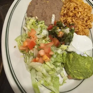 The sides for the fajitas. Sour cream, guacamole, rice, beans, lettuce, tomato, and pico de gallo