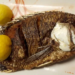 a whole fish on a plate with lemons