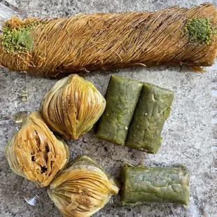 Diyarbakir Burma (top long pastry), shell baklava with pistacho (bottom left), and pistachio roll (green short rolls on at the bottom right)