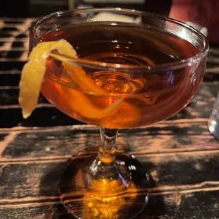a cocktail in a coupe glass with an orange peel