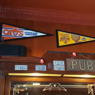 a bar with a clock and pennants on the wall