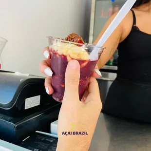a hand holding a cup of fruit smoothie