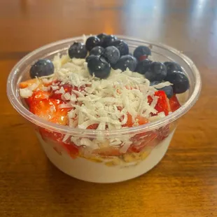 Coconut base bowl with granola, strawberry's, blueberries, coconut shavings and honey.
