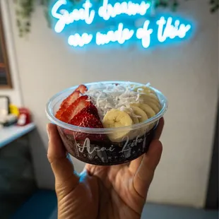 a hand holding a bowl of fruit