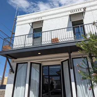 a white building with a balcony and a black door