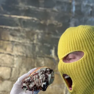 a person wearing a ski mask and holding a sandwich