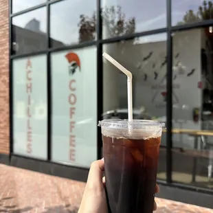 a hand holding a cup of iced coffee