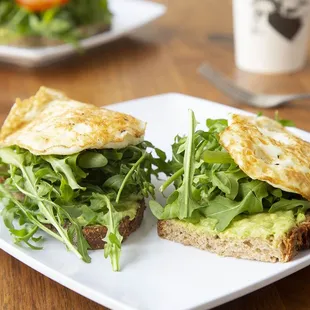 Avocado toast with arugula and over medium eggs