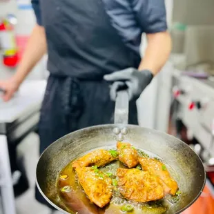 a chef holding a frying pan of food
