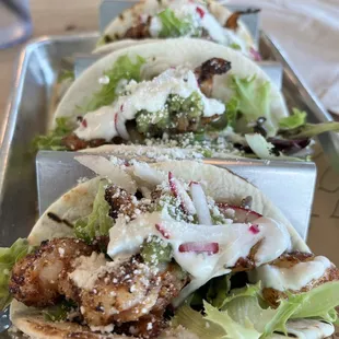 three tacos on a tray with lettuce