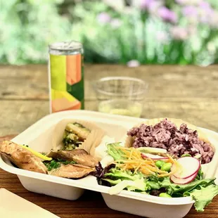 a tray of food and a drink on a wooden table