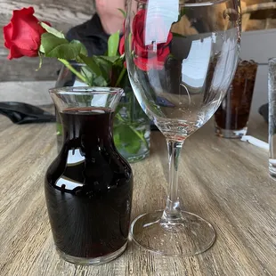 a glass of wine and a vase of red roses