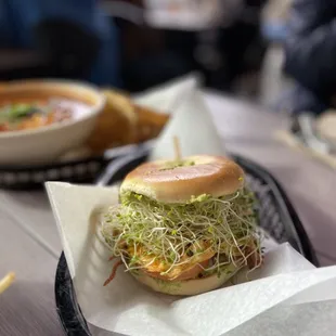 a sandwich with sprouts and a bowl of soup