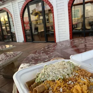 Three rolled beef tacos with rice and beans