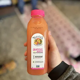 a person holding a bottle of orange juice